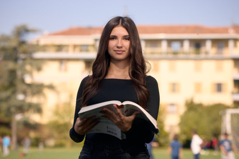Studentessa con un libro sul campo sportivo