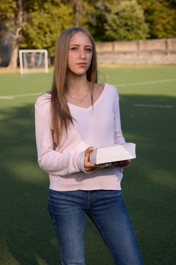 Studentessa con un libro sul campo sportivo