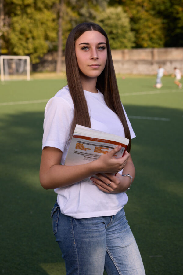Studentessa con i libri sul campo sportivo