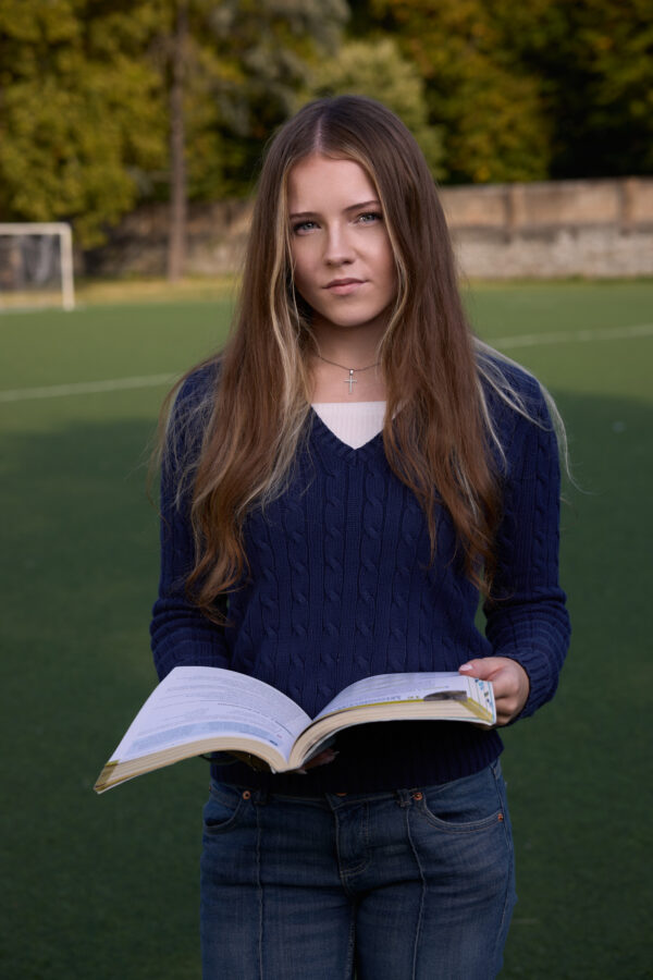 Studentessa con un libro sul campo sportivo